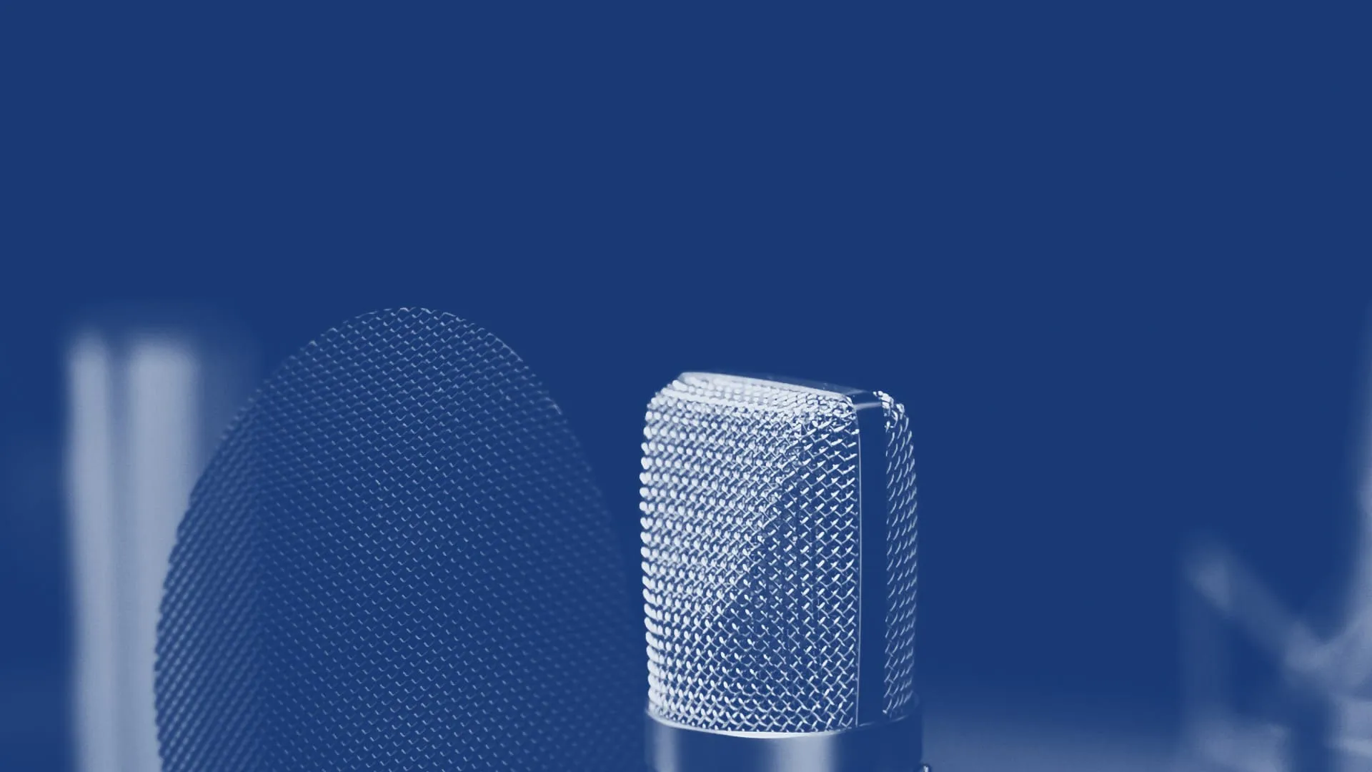Primo piano di un microfono da studio a condensatore accanto a un filtro anti-pop, su fondo scuro, in duotono blu