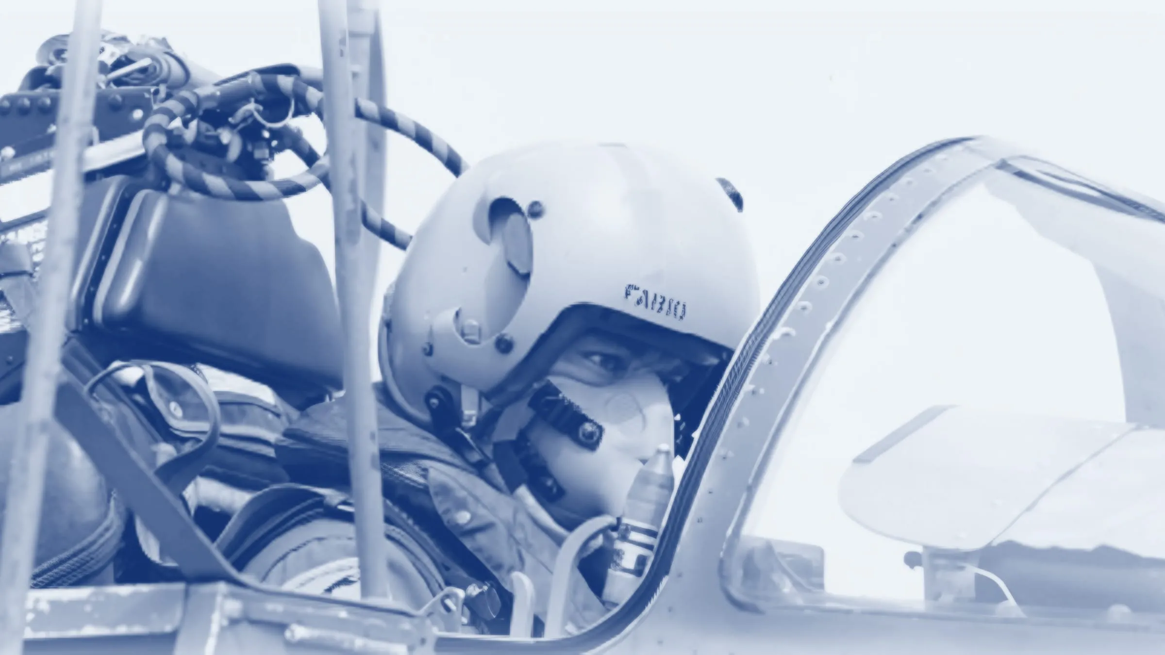 Fabio Masci nell'abitacolo di un caccia, con il casco di volo che porta il suo nome e la maschera per l'ossigeno, virato in blu