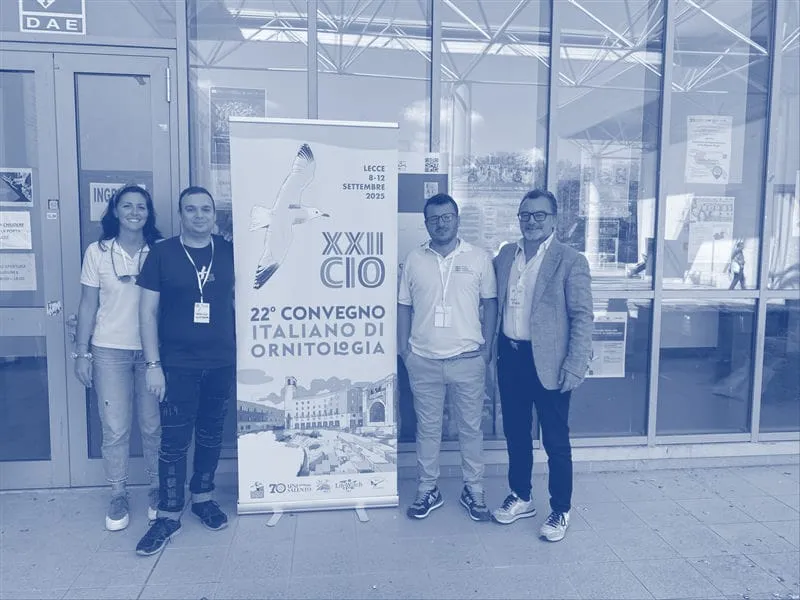 Il team e i biologi accanto allo striscione del convegno a Lecce, in duotono blu
