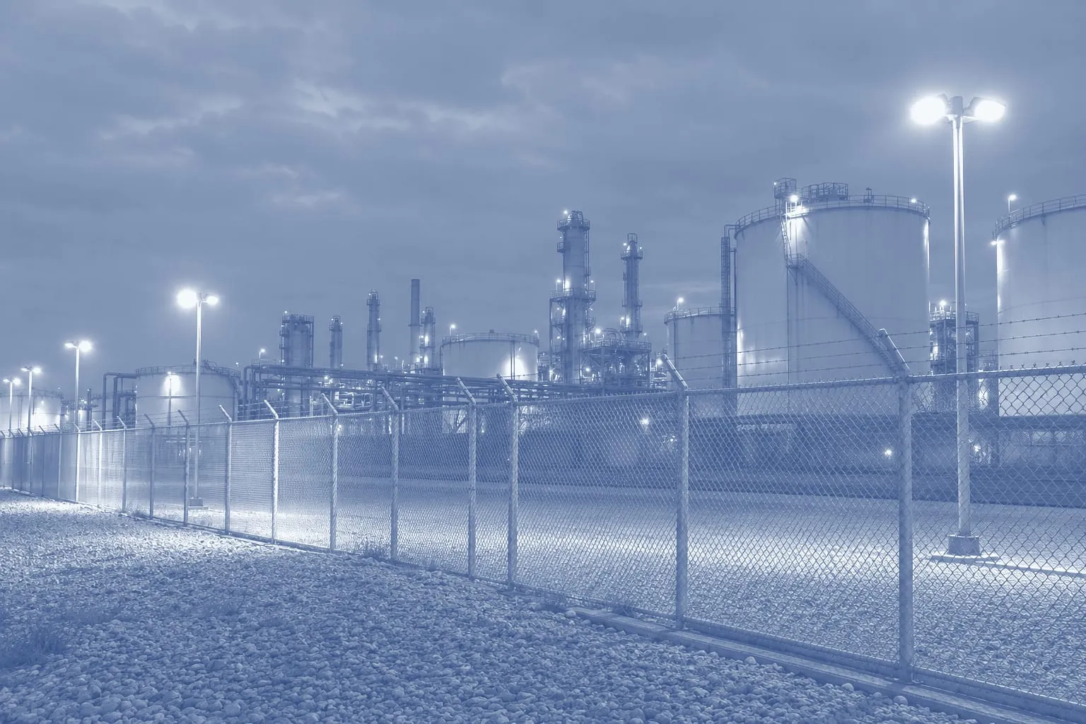 La recinzione illuminata di un impianto industriale di notte, serbatoi e tubazioni sullo sfondo, un'illustrazione stampata in duotono blu